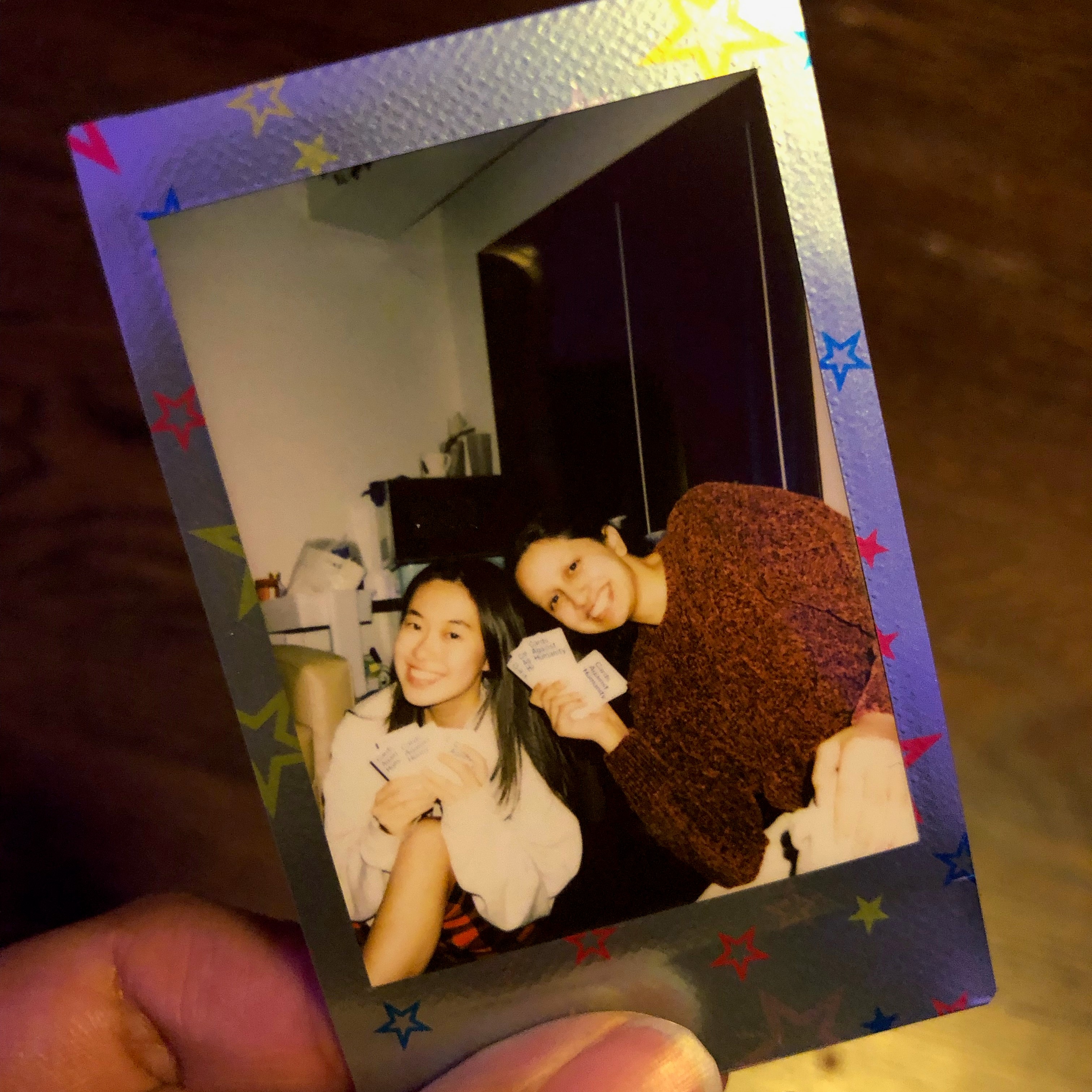 a polaroid photo of kelly and priya playing cards against humanity