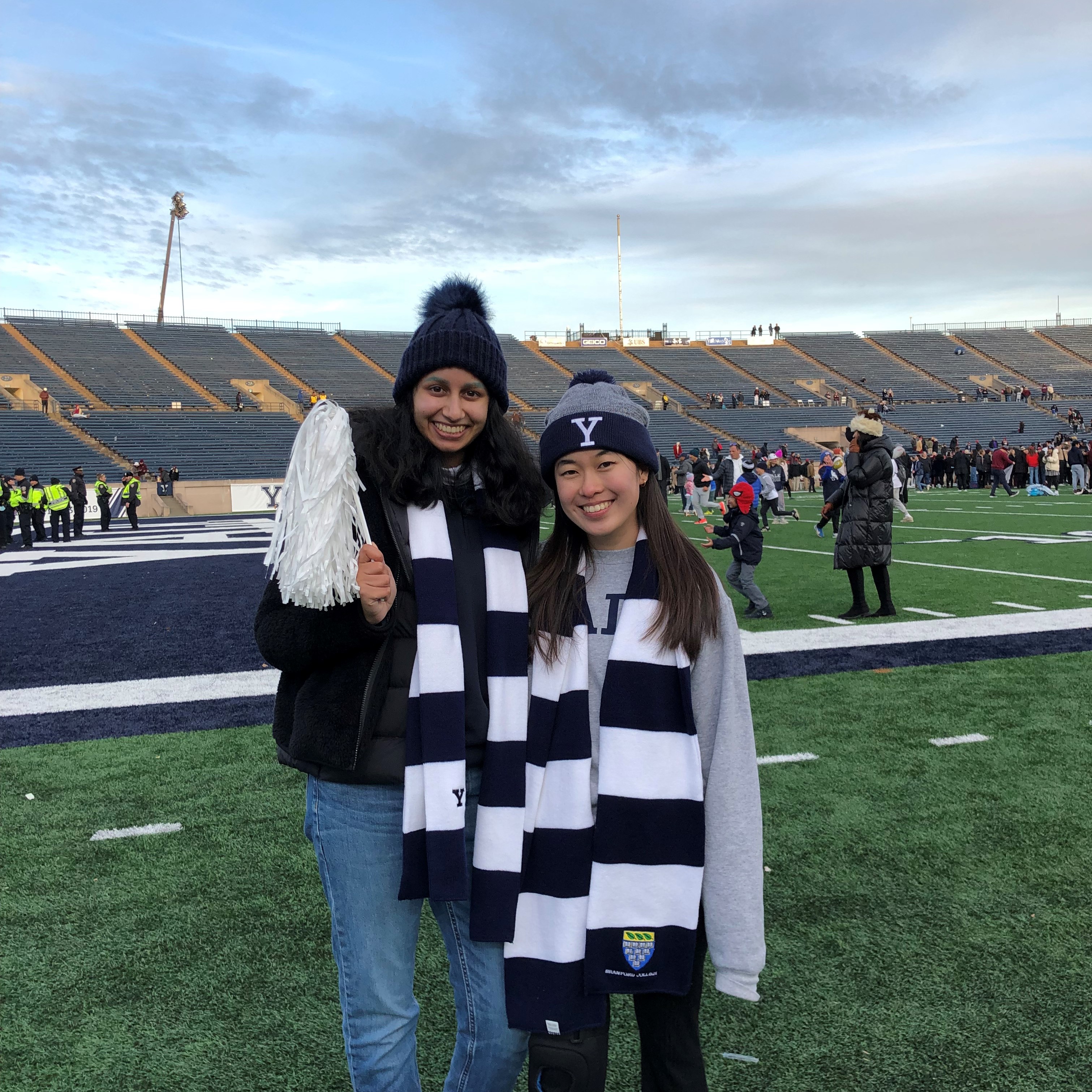 priya and kelly decked out in yale scarves and hats on the grass